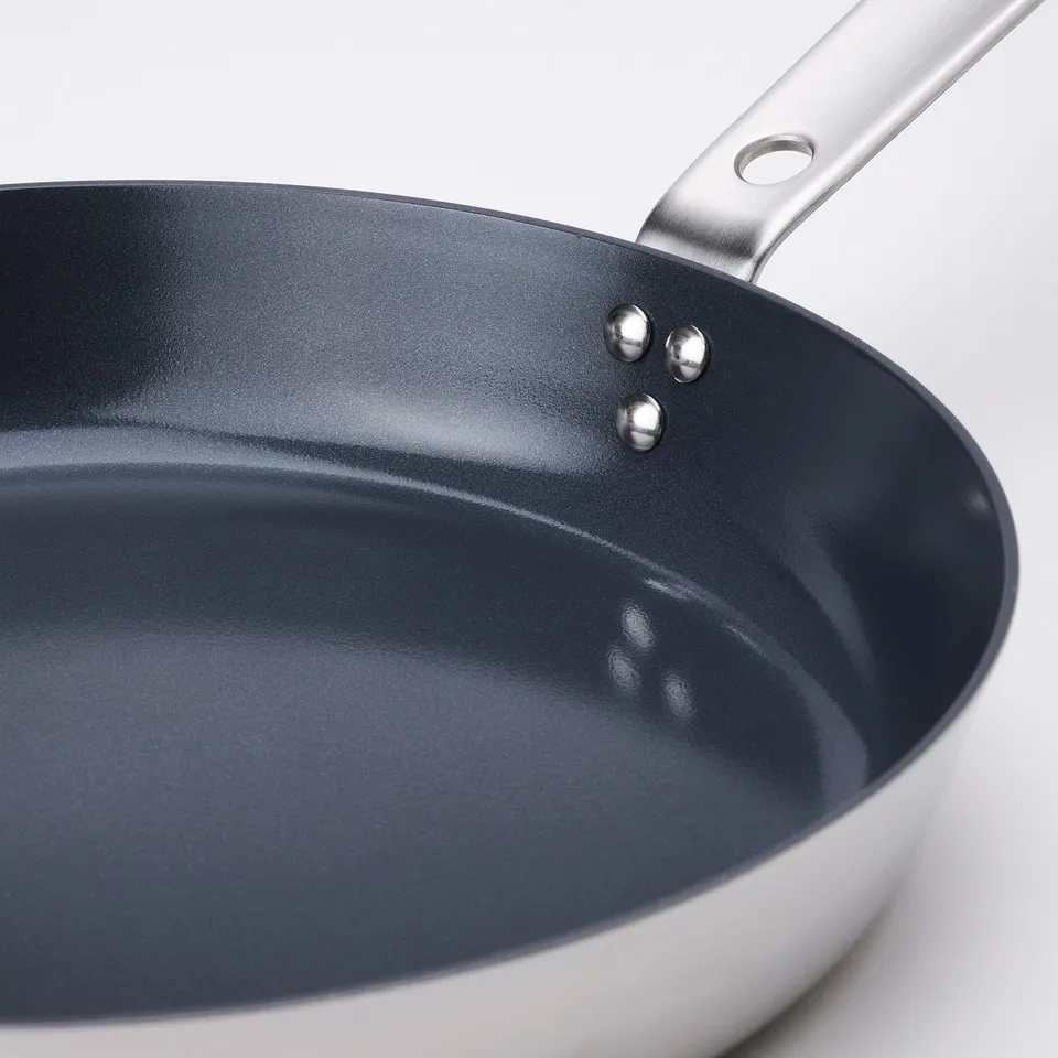 Non-stick frying pan with stainless steel handle. Smooth, dark interior shows high quality finish.