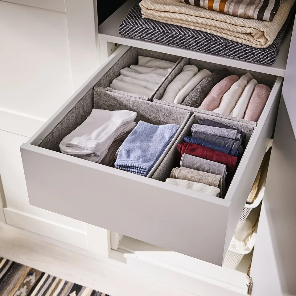 Organised drawer with white KOMPLEMENT felt boxes storing folded clothes in a wardrobe.