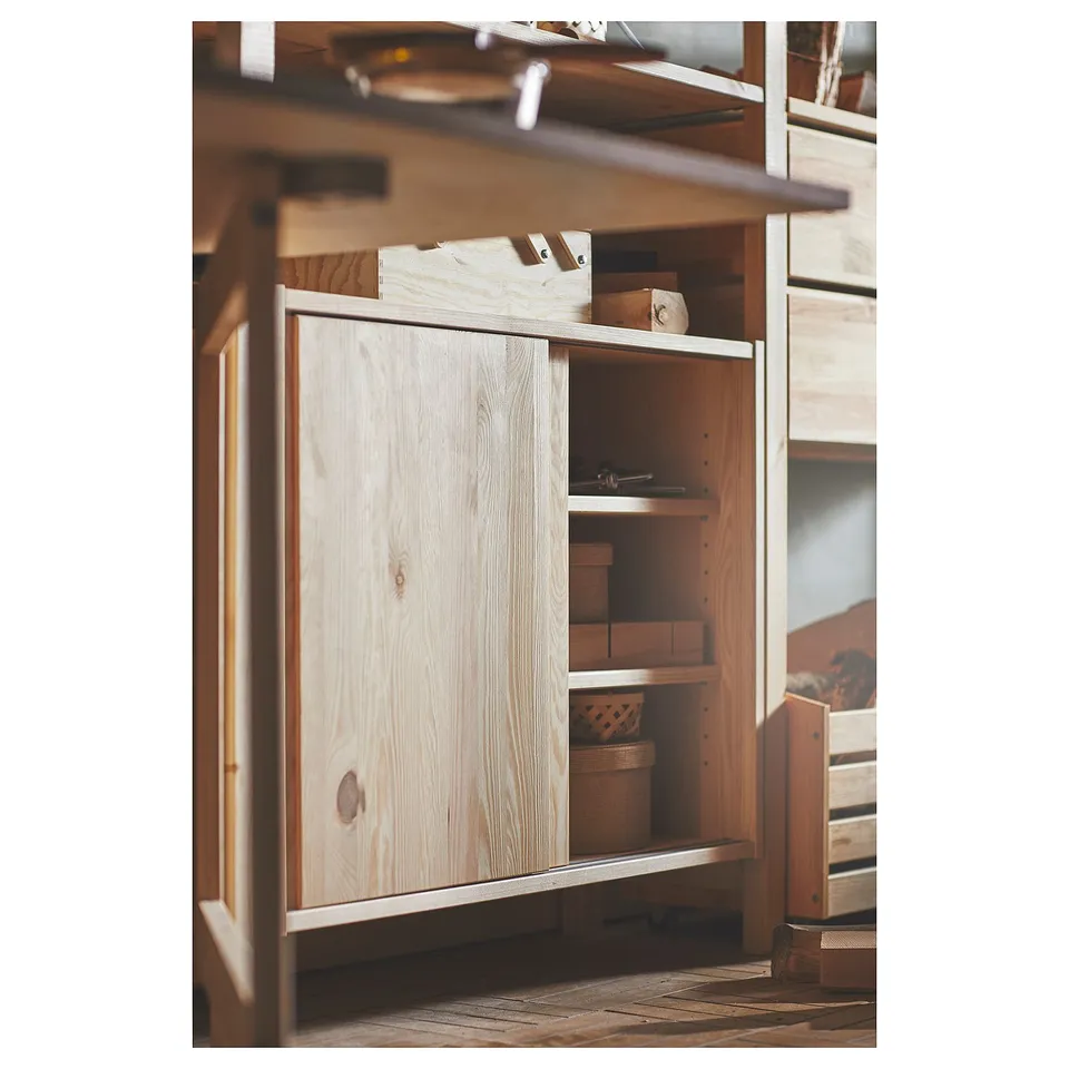 Natural wood IVAR storage unit with sliding door and wicker baskets, showcasing rustic design.