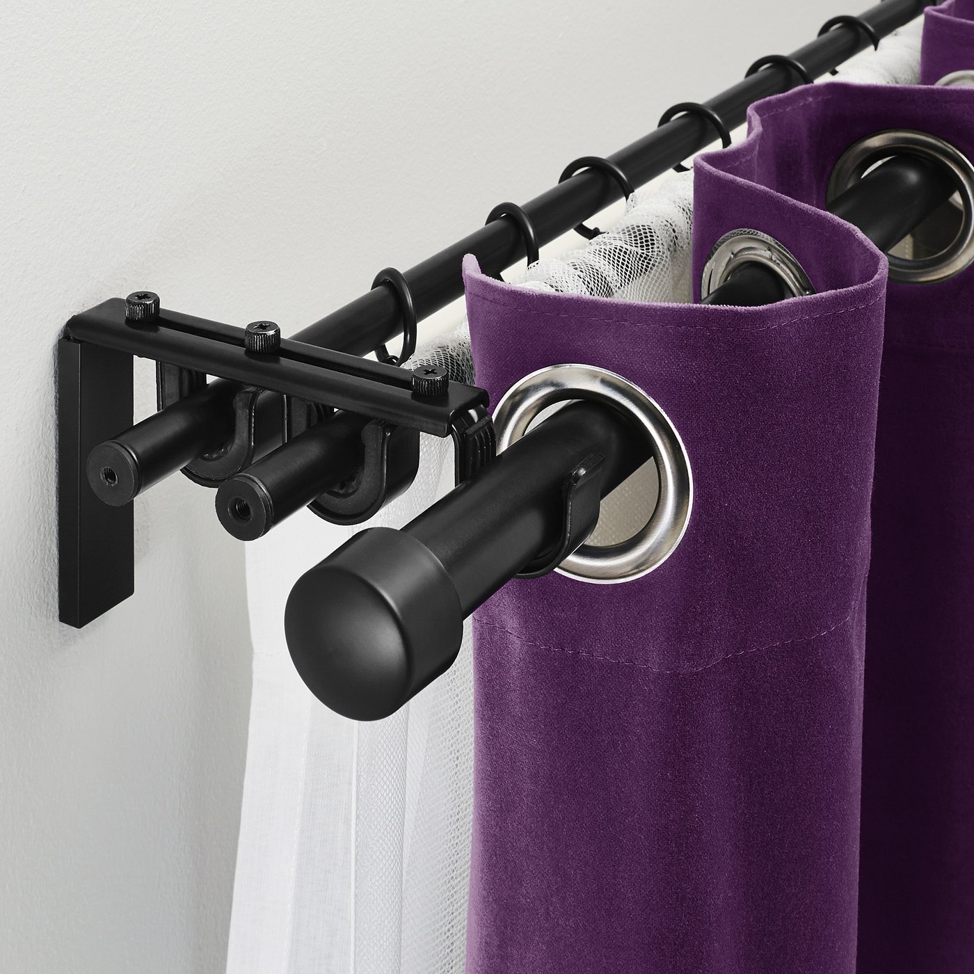 Black curtain rod system with purple curtains and silver rings, showcasing triple rod capability for layered curtains.