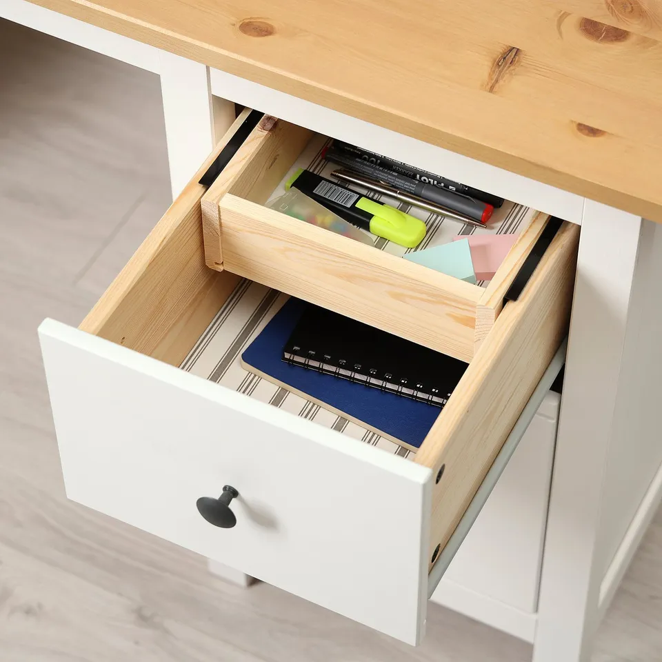 Open desk drawer showing organised stationery with pens, notepad, and files, highlighting storage and organisation.