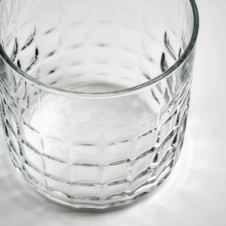 Textured glassware, elegantly faceted, reflecting light. Shows intricate, diamond-like pattern.