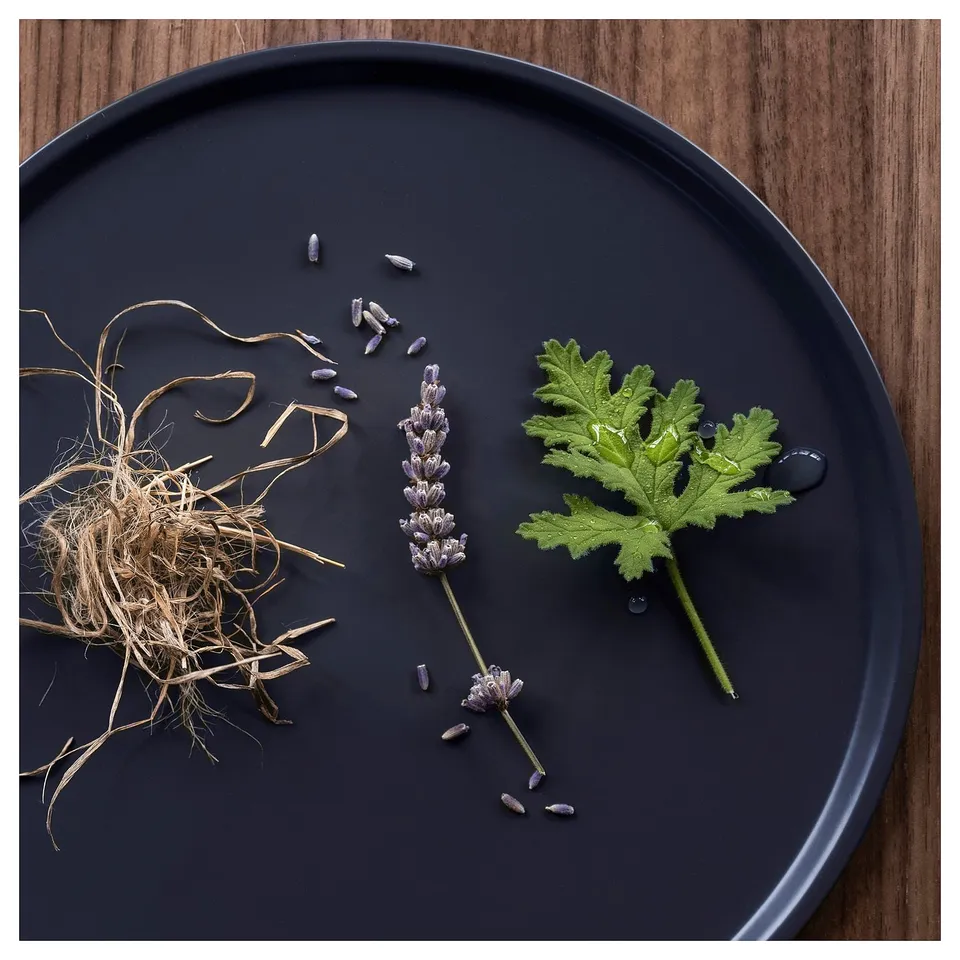 Black plate with lavender, leaves, and dried plant material. Minimalist design, natural elements.