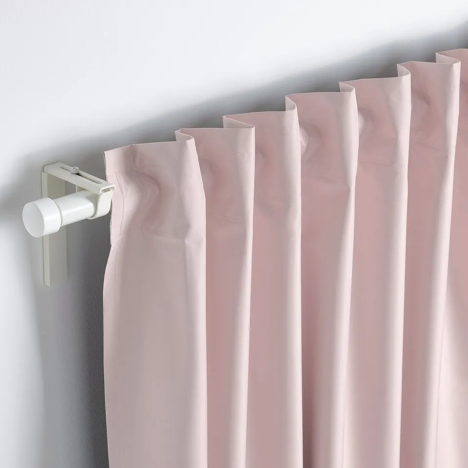 Close-up of light-blocking, peach-colored curtains with a rod pocket, hanging neatly.