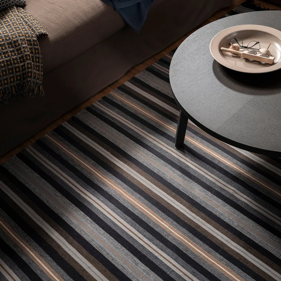 Striped RÅVAROR rug under sofa & table with remotes.