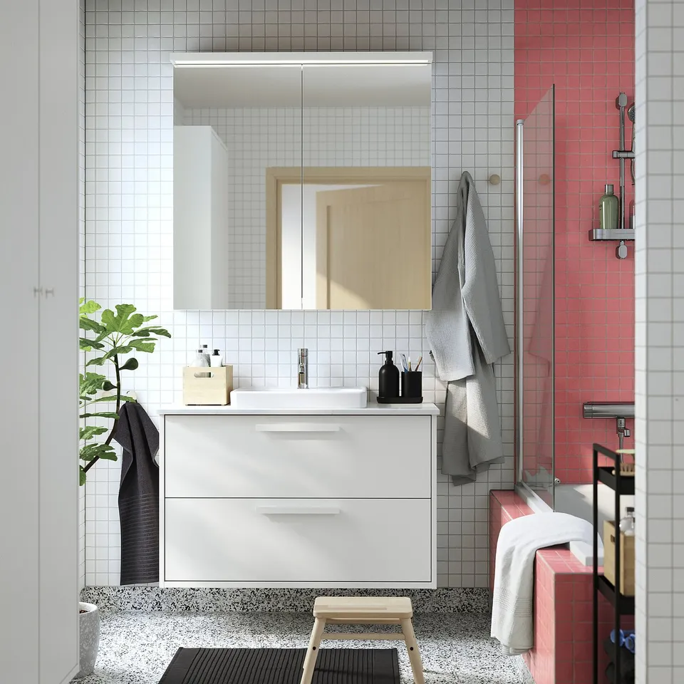 Modern white bathroom with HAVBÄCK vanity, soft basin, red-tile shower, grey towels, plant, and stool.