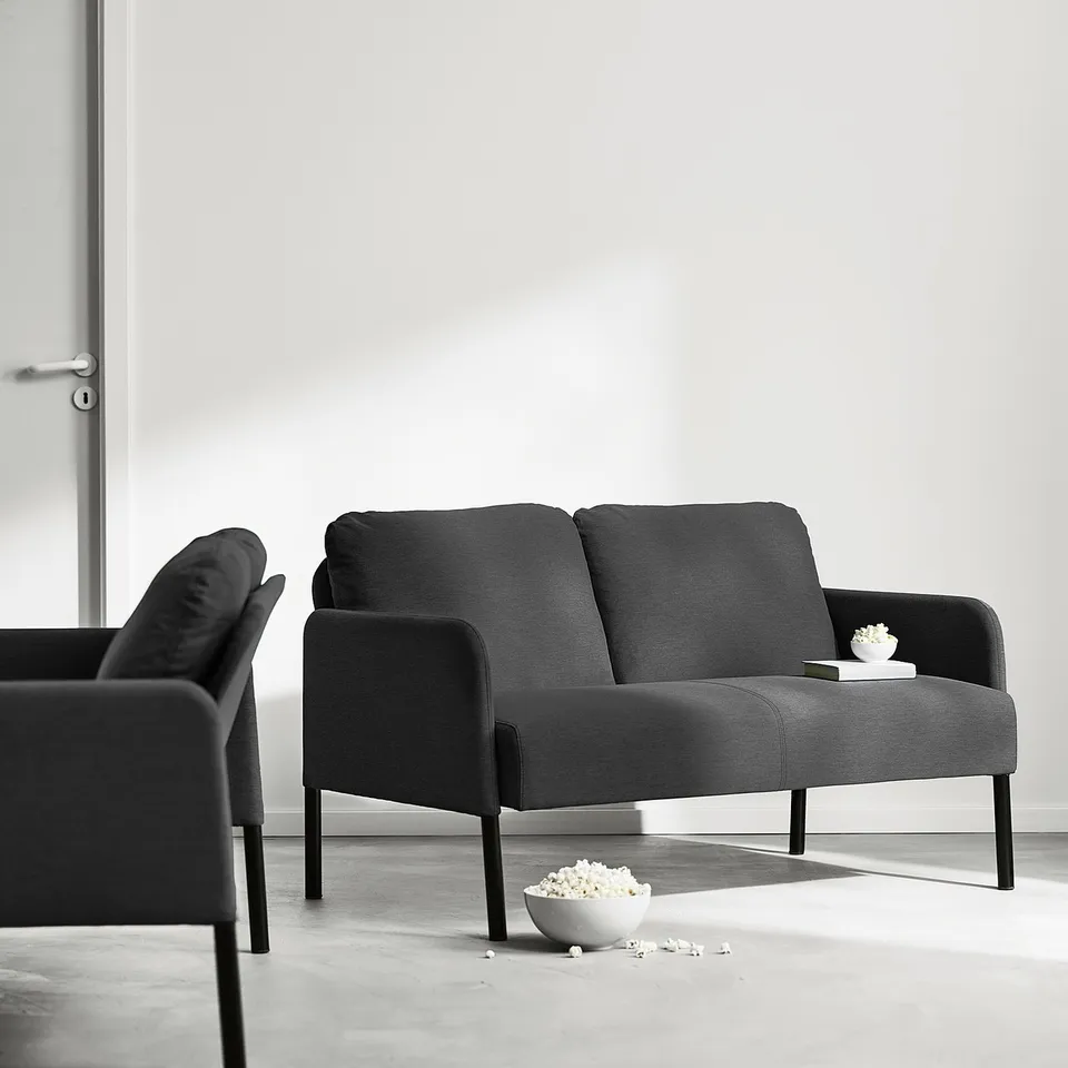 Modern minimalist living room with a grey GLOSTAD sofa and matching chair, simple design, clean lines, durable fabric.