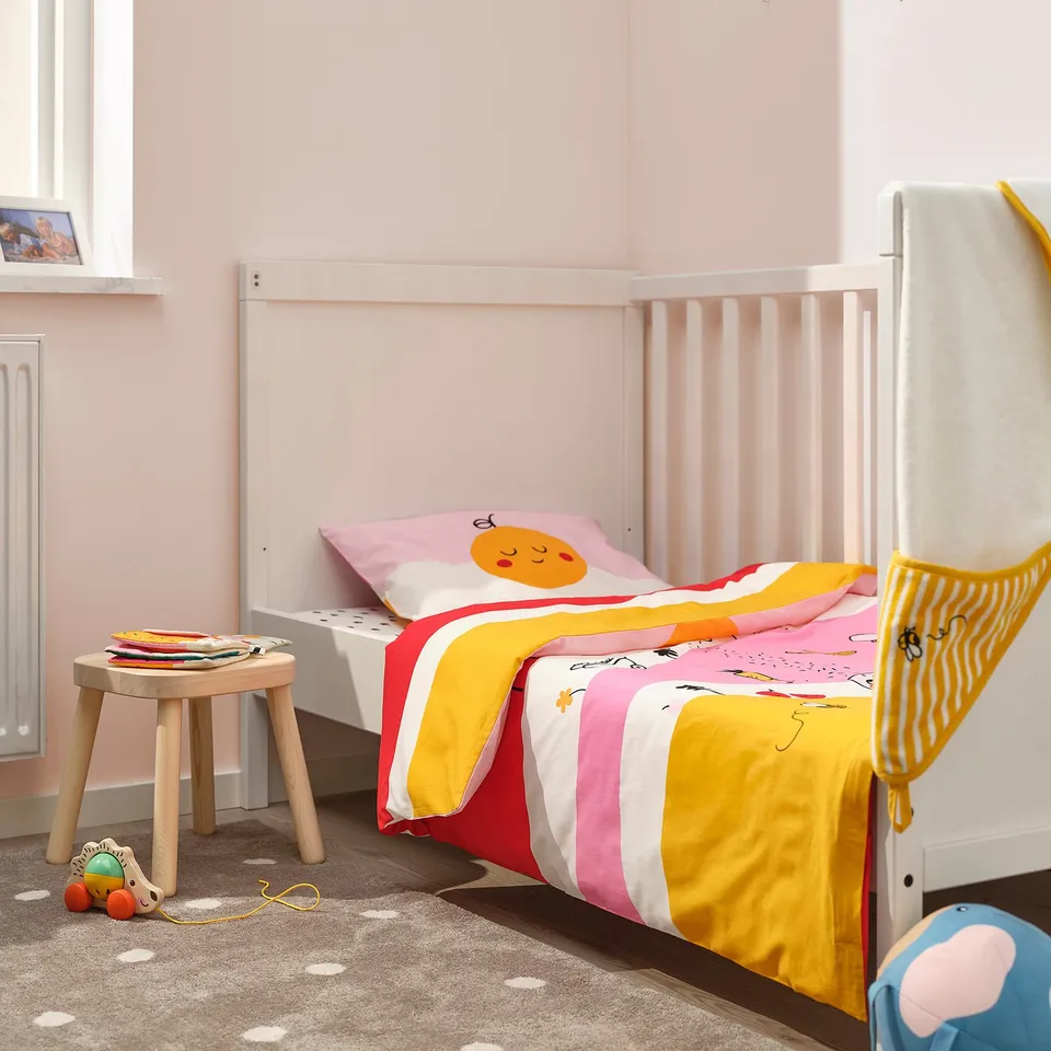 Cosy kids room with GRÖNFINK striped duvet, toy, and pink walls.