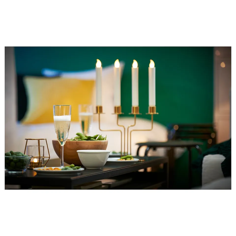 Elegant silver candelabra with 4 lit candles, chic decor on dark table, refined dinner setting.