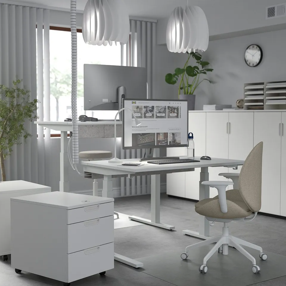 Minimalist white MITTZON sit/stand desk; modern, clean design; compact yet spacious; raised work surface; ergonomic chair; sleek office setup.