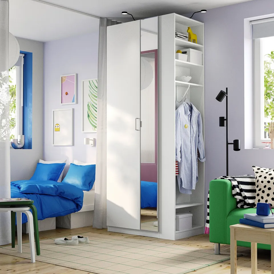 Modern bedroom with white PAX wardrobe, mirrors, and green chair.