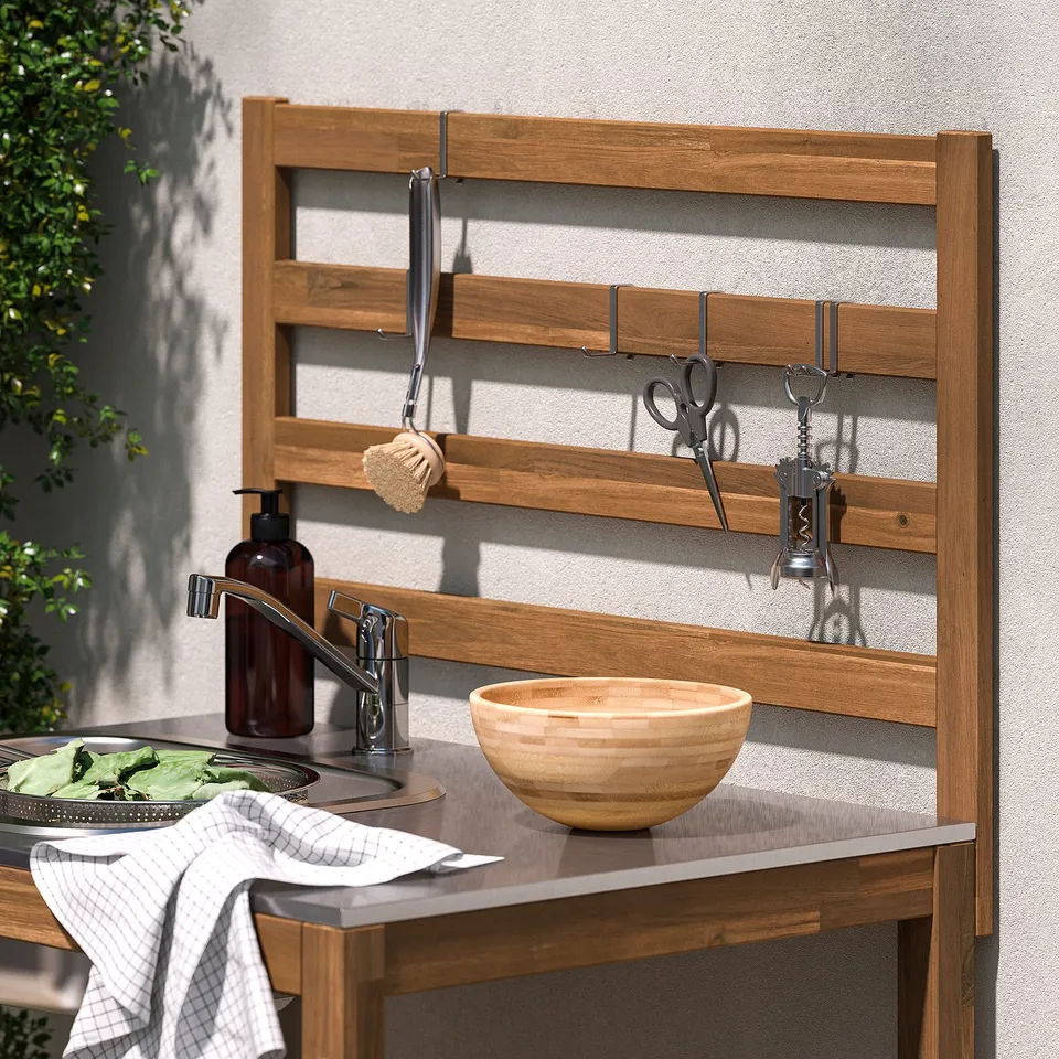 Outdoor kitchen sink with hooks for utensils and a bowl on the counter.