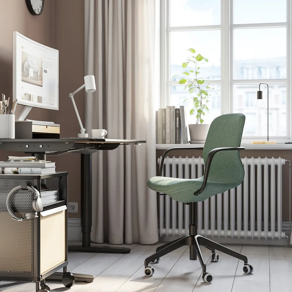 Green LÅNGFJÄLL office chair in workspace with adjustable positioned near desk and window.