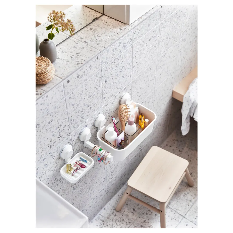 Bathroom with TISKEN wall-mounted organiser holding toiletries and jewellery on speckled tiles, wood stool below.