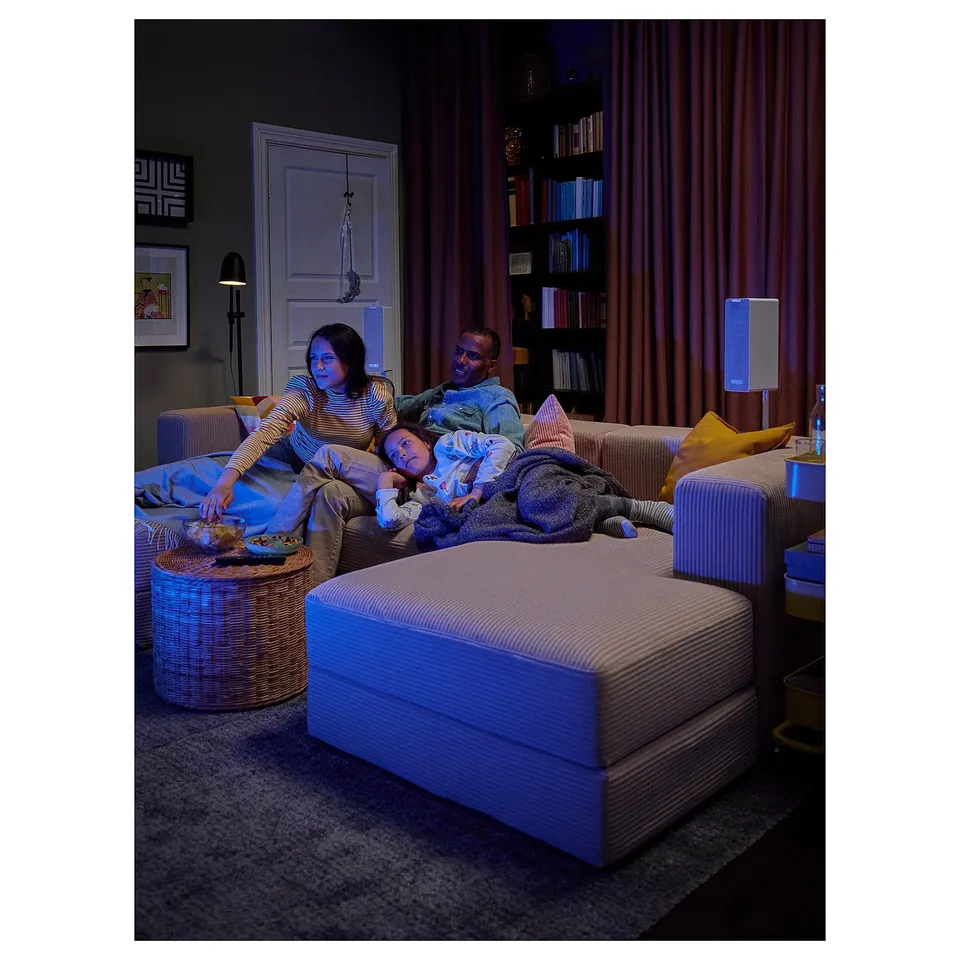 Cosy family on blue-toned JÄTTEBO modular sofa, with books and blankets, enjoying a relaxed moment.