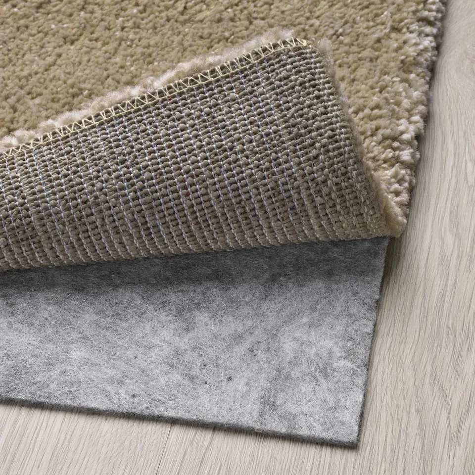 Grey rug with thick, soft pile and light sheen, backed with anti-slip felt pad for stability.