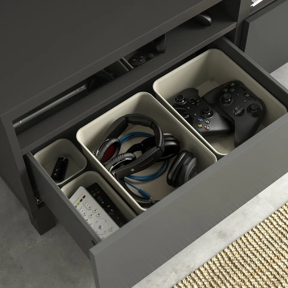 Open grey BESTÅ tv drawer organises remote, controllers, headphones.