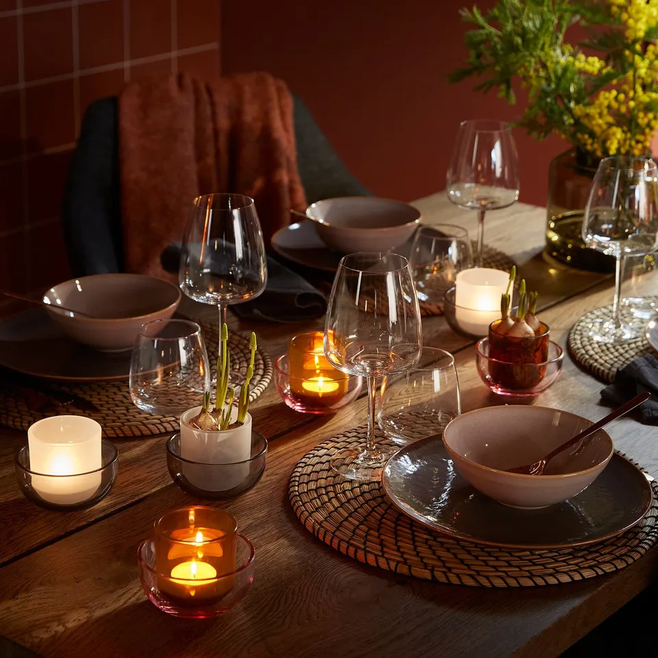 Elegant table setting with TALLTITA tealight holders, warm colours, cosy ambiance, plates, and wine glasses.