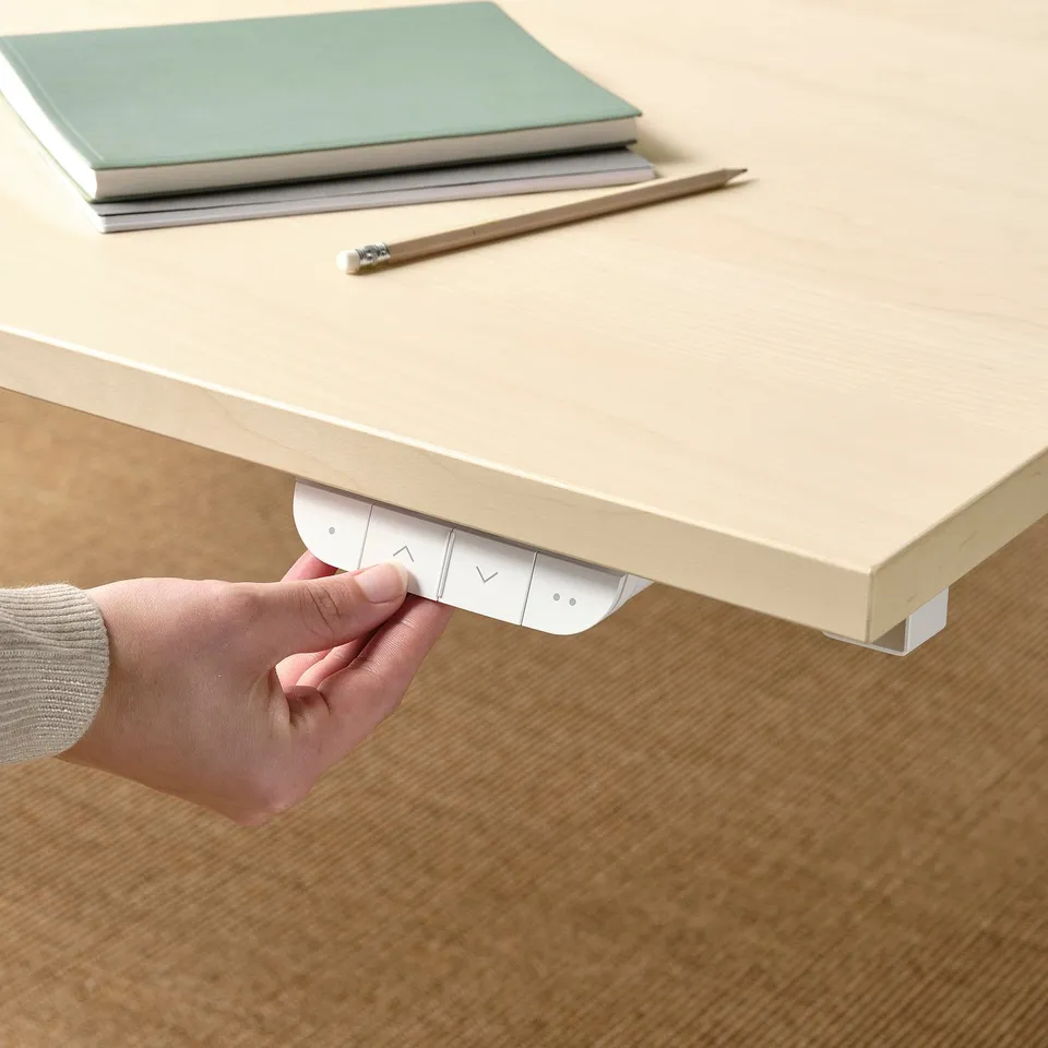 Persons hand adjusting control panel under sit/stand desk, adjusting height.