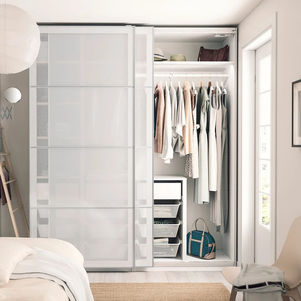 Bedroom with white PAX wardrobe, clothes, handbag, ladder, and lamp.