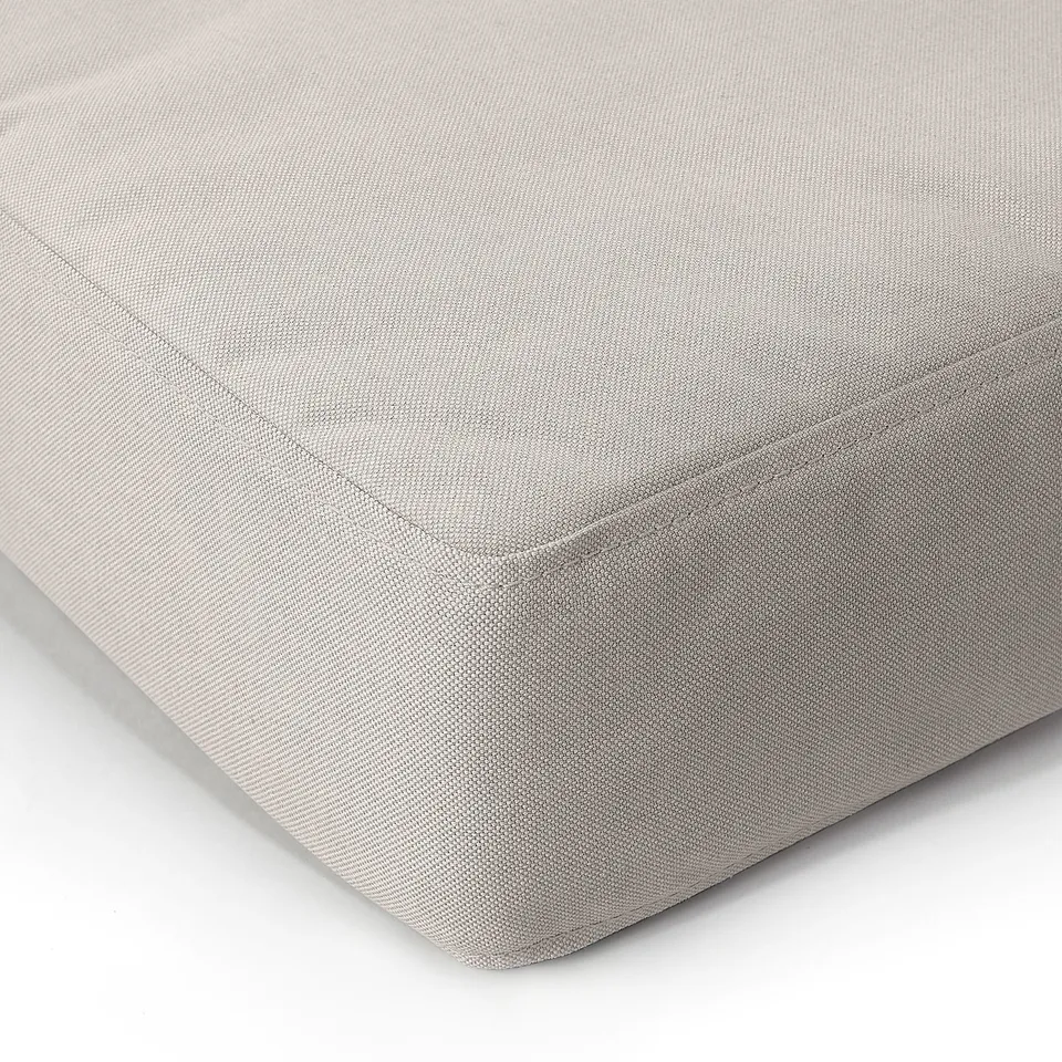 A close-up of a plush, textured cushion with neatly stitched edges, showcasing its soft, inviting fabric quality.
