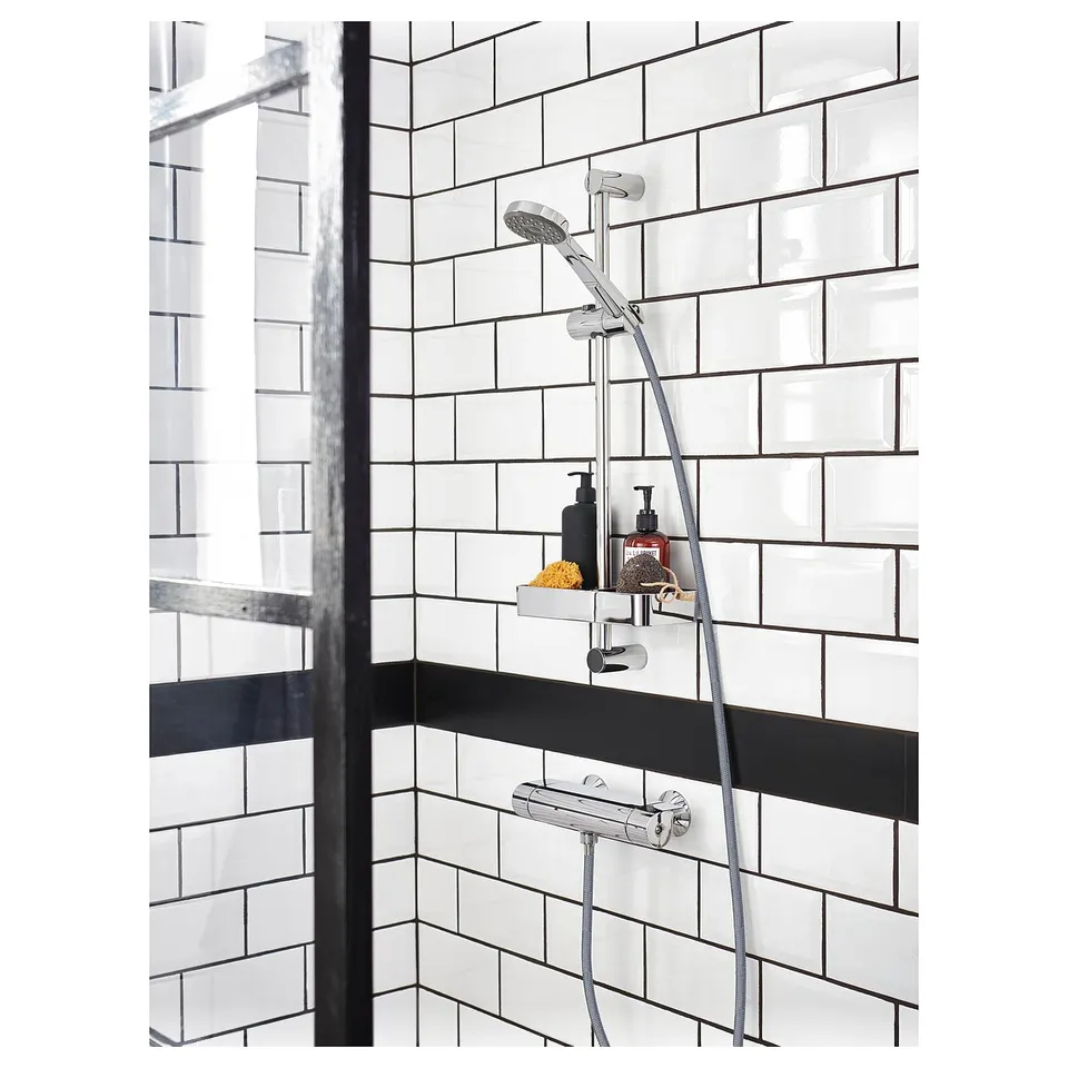 Modern black and white tiled shower with chrome BROGRUND shower head and shelf.