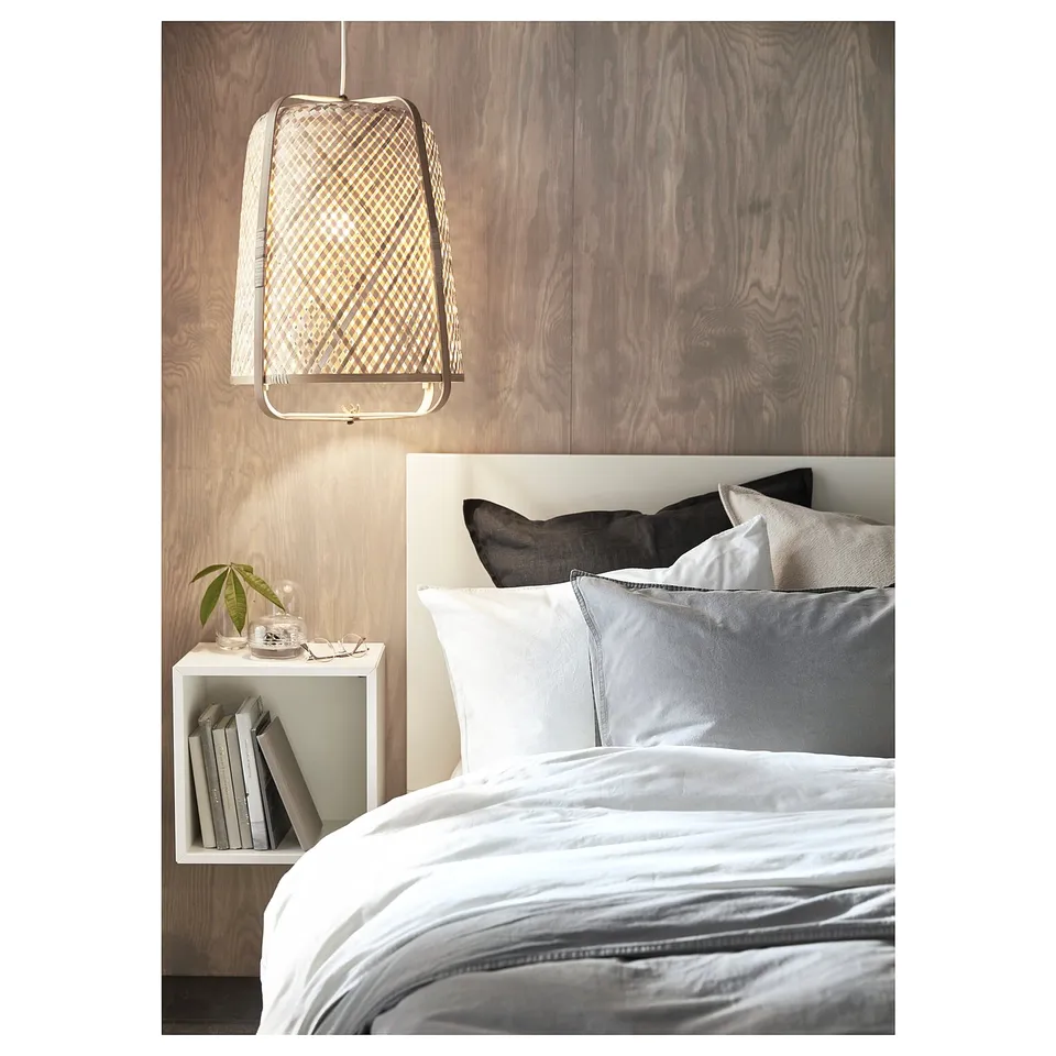 Modern bedroom with white EKET bedside table featuring grey bedding, hanging pendant light, and books on the bedside table.