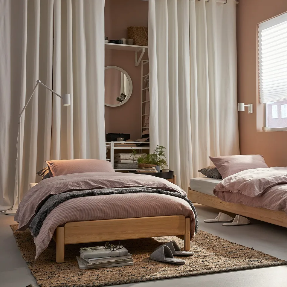 Cosy bedroom with two light wood UTÅKER beds in neutral tones, soft lighting, and natural decor.