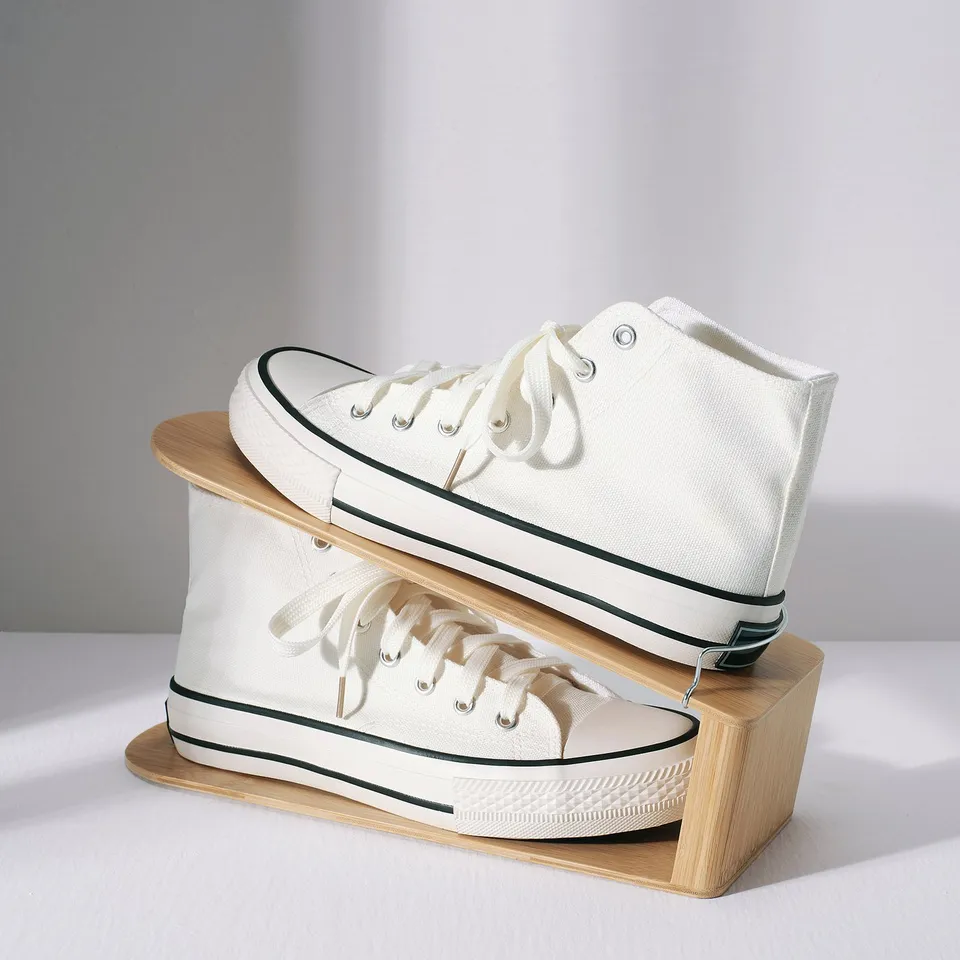 White trainers stored vertically on wooden stand.