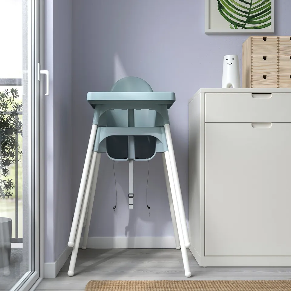 Baby highchair, light blue seat, white legs, near window. Easy to disassemble, secure edges.