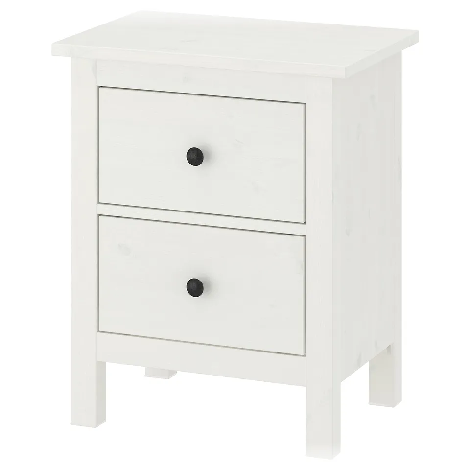 A white HEMNES wooden chest of drawers with two drawers, each having black knobs, standing on four legs.
