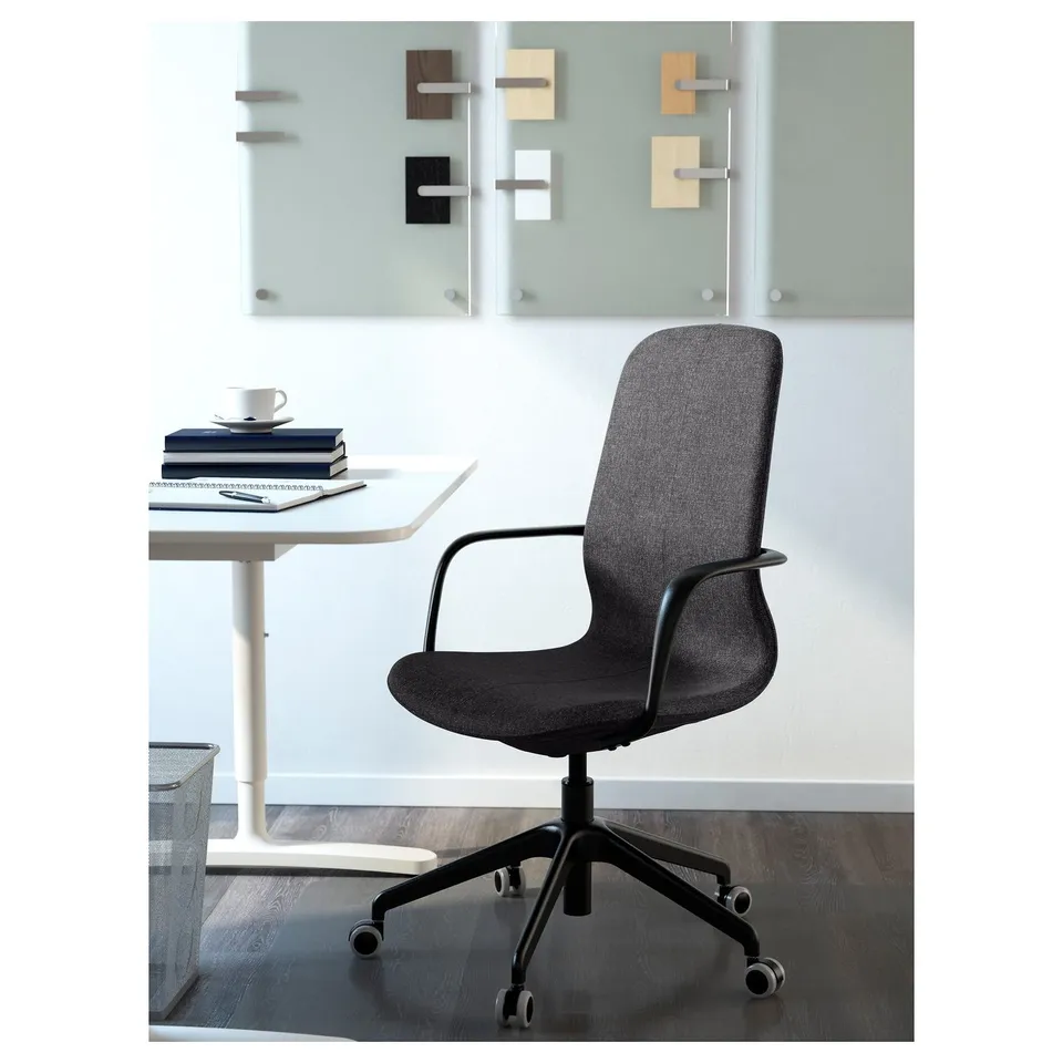 Modern office setup with LÅNGFJÄLL chair and table with books and cup.