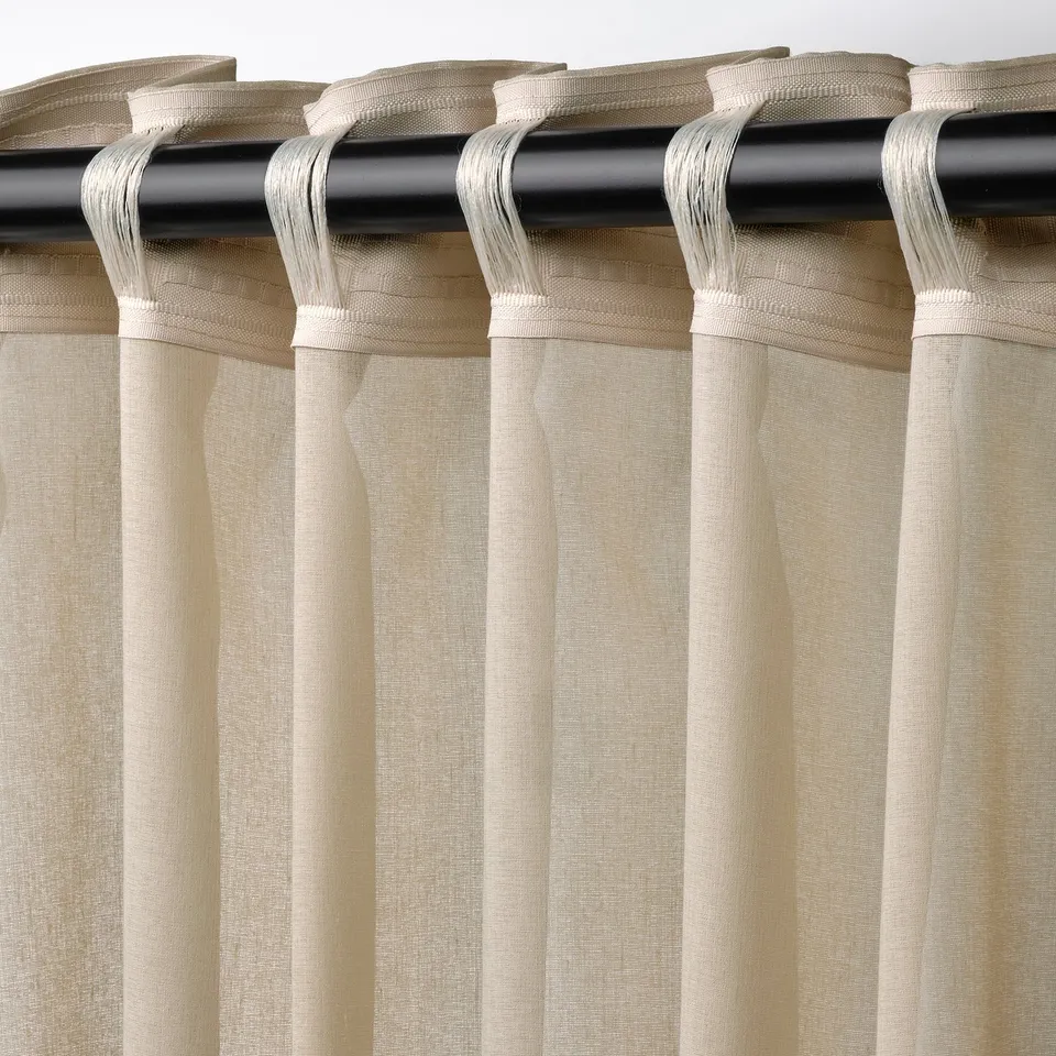 Beige sheer curtains with rod pocket header, filtering light and offering privacy.