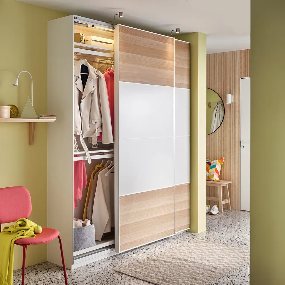 Modern closet with KOMPLEMENT clothes rail, light wood and white panels, hanging clothes, integrated lighting.