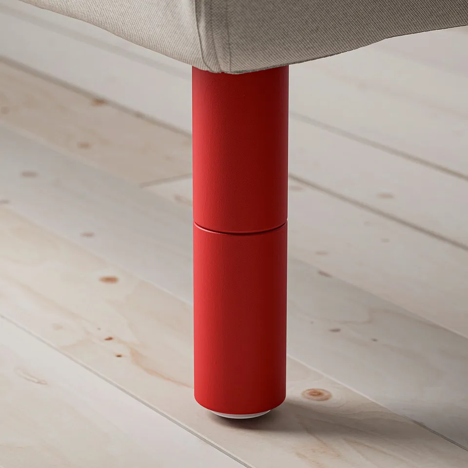 Abstract chair leg detail, focusing on the quality and texture of the bright red cylindrical leg and grey upholstered seat.