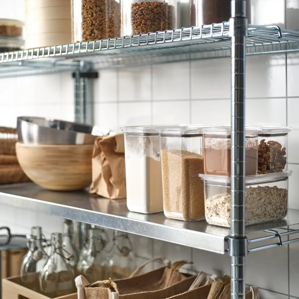Clear containers with airtight lids store dry foods, preserving freshness. Shelf includes various sizes for grains, nuts, and seeds.