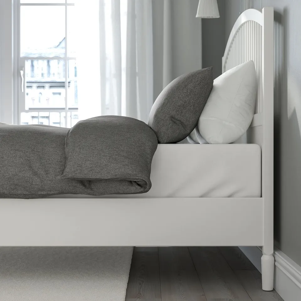 Adjustable white bed with grey bedding, high headboard, and under-bed storage.