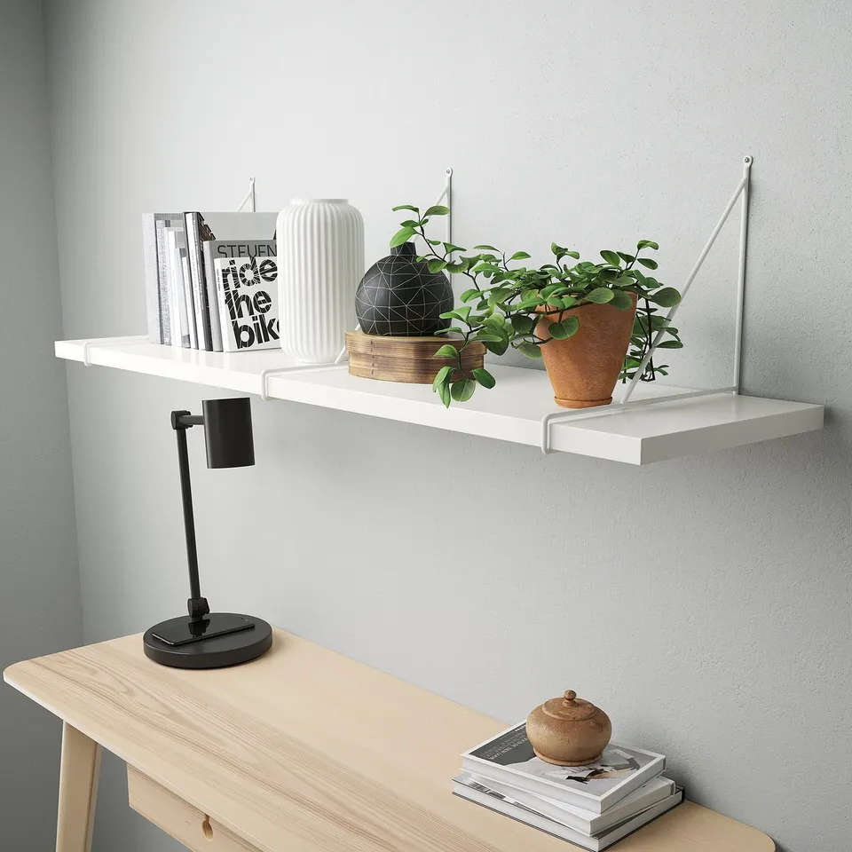 Shelf with books, vase, plant; lamp on wooden table.