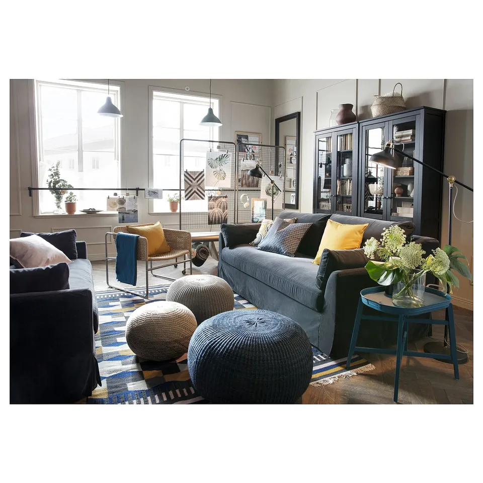 Modern living room with grey SANDARED pouffes. Large windows, blue accents, and cosy decor.