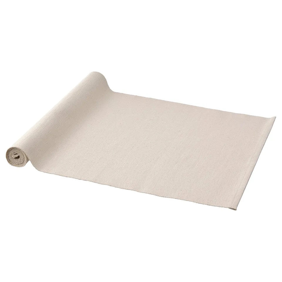 A rolled-up white cotton table runner named SVARTSENAP. Its plain and rectangular.