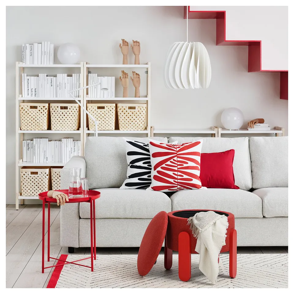 Cosy living room with grey sofa, red pillows, and FÖRLUNDA red footstool for extra seating and storage.