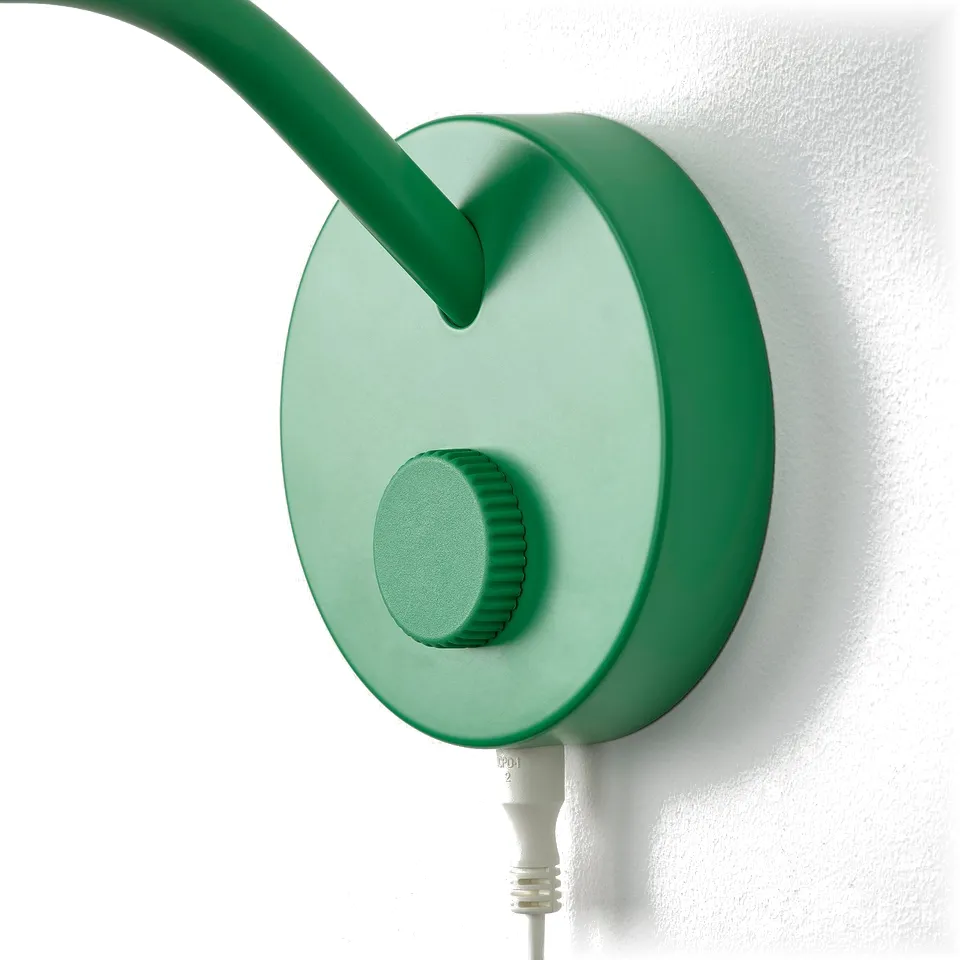 Green wall-mounted lamp with adjustable neck and circular base; modern, sleek design.