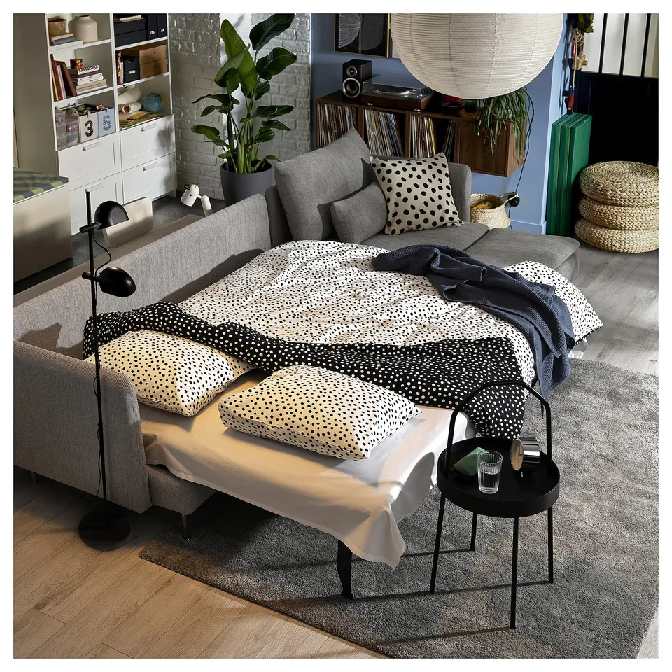 Modern living room with grey SÖDERHAMN sofa-bed featuring polka dot pillows, open shelves with books and plants, and a record player.