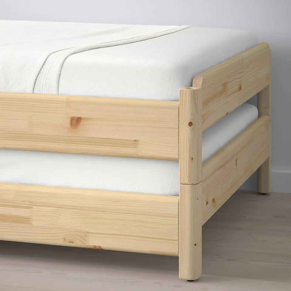 A wooden twin bed frame with a white mattress. The frame is designed to stack and convert into different configurations.