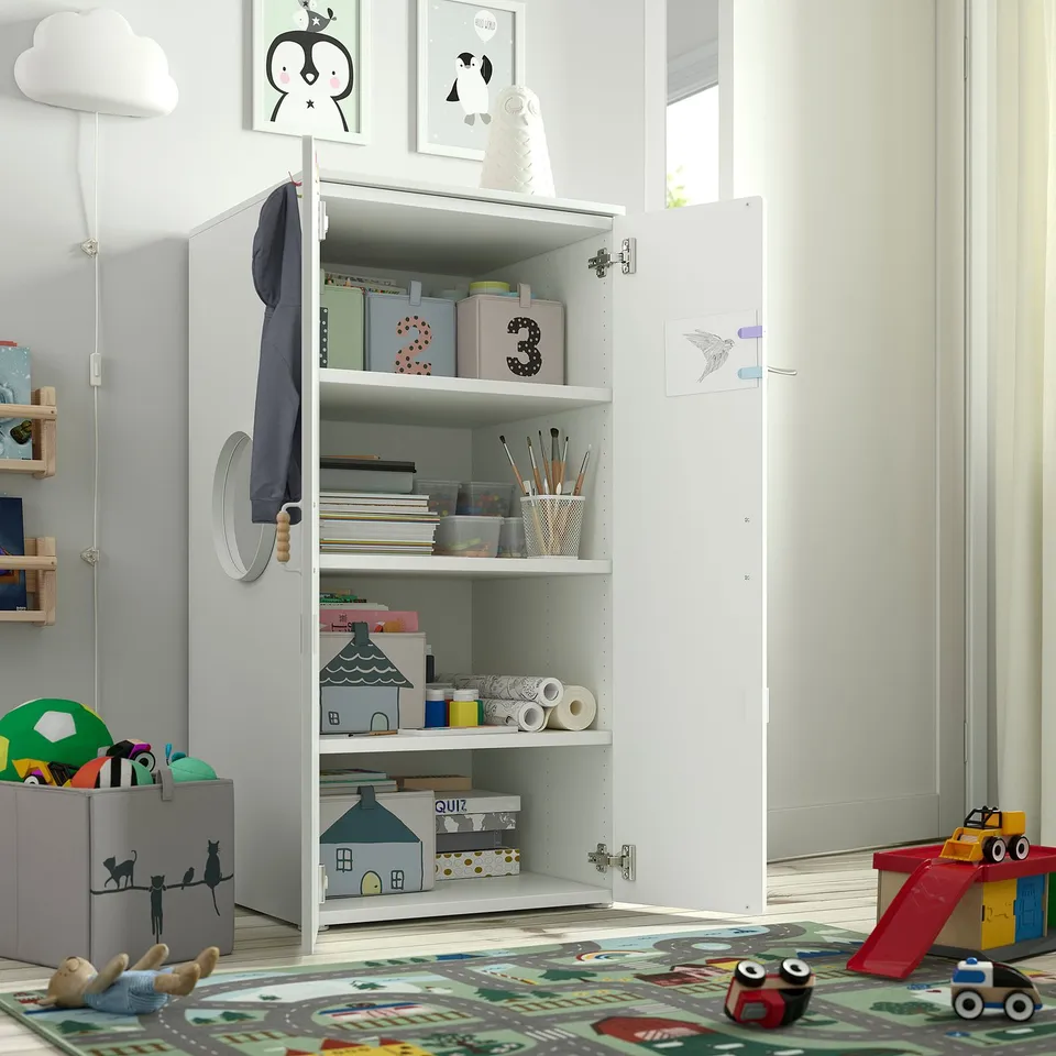 Kids cabinet with open doors, toys, books, crafts on shelves. Colourful rug, toys nearby.