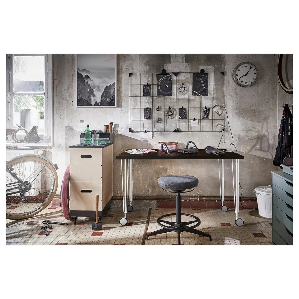 Industrial-style workspace with LAGKAPTEN table, stool, bike, tools, and wall decor.