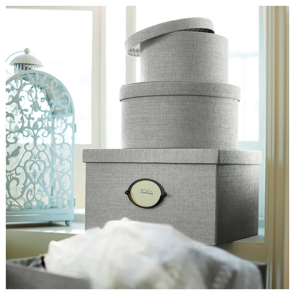 Stacked grey KVARNVIK boxes near window, light blue decorative lantern.