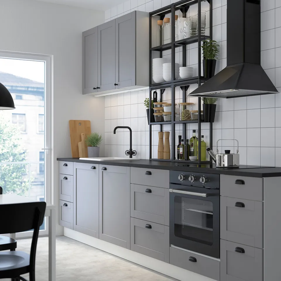 Modern grey kitchen with hanging sleek black lamp, open shelves, and various containers and plants.
