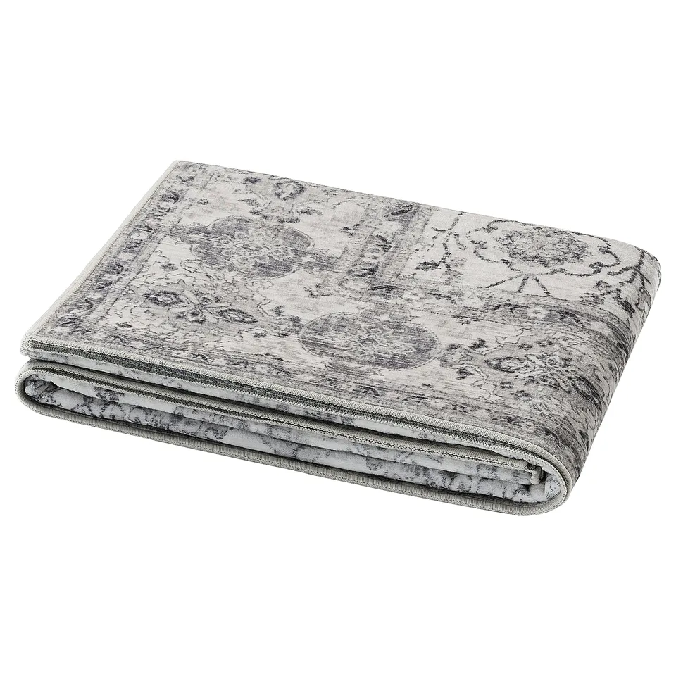 A folded grey LOKALTÅG yoga mat with intricate texture and floral design, made from eco-friendly materials.