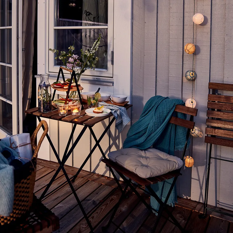 Wooden balcony with lanterns, table, chairs, candles, and flowers - cosy.